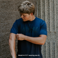 Person wearing a blue t-shirt against a textured wall